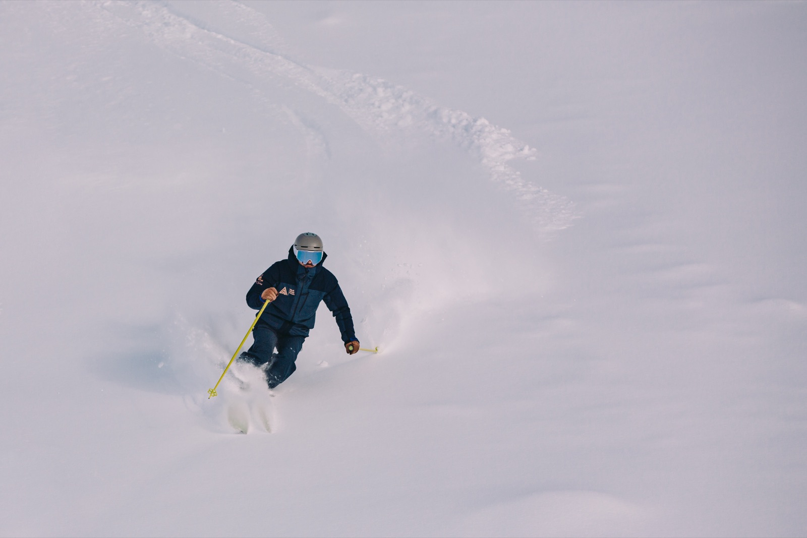 A lone Peak skier carving deep powder.
