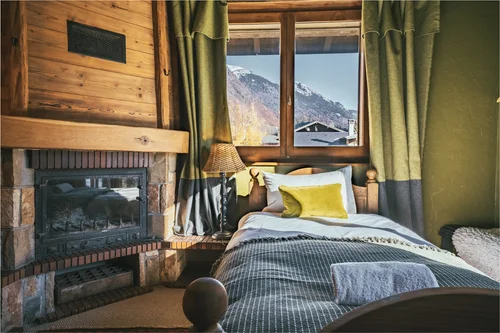 A wood-panelled bedroom with fireplace and mountain view at The Fat Fox Lodge